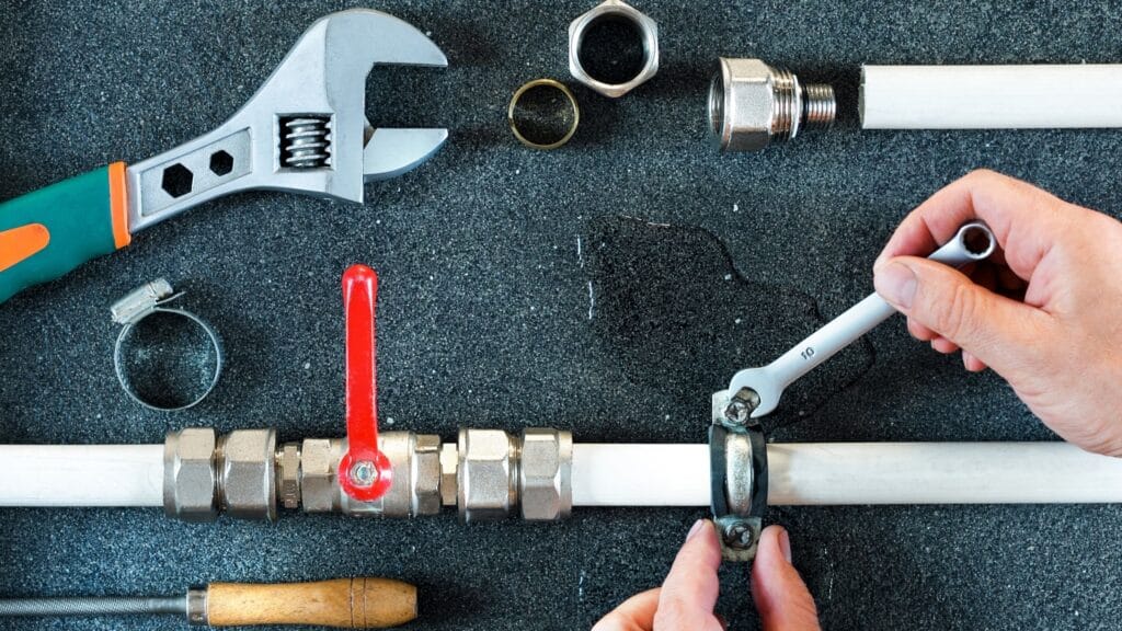 Plumber repairing a pipe valve with an adjustable wrench in Corvallis