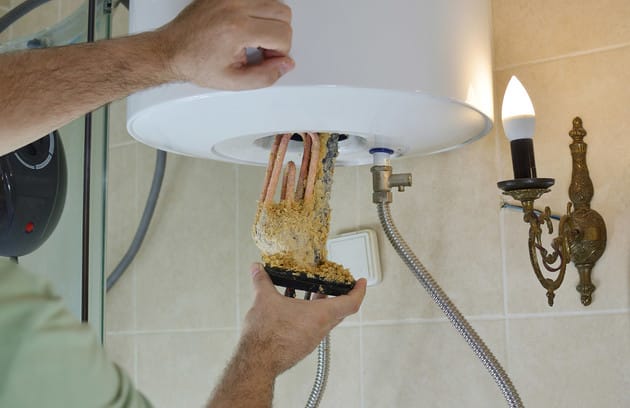 Technician removing mineral buildup from a water heater in Corvallis