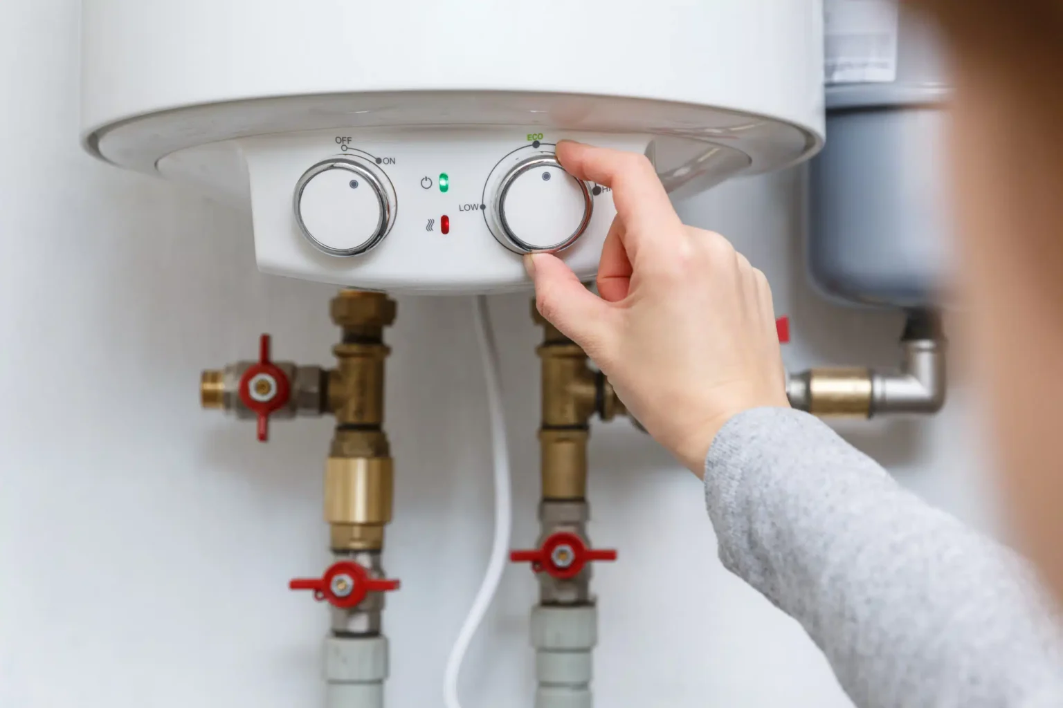 Homeowner adjusting the temperature controls on a water heater in Corvallis
